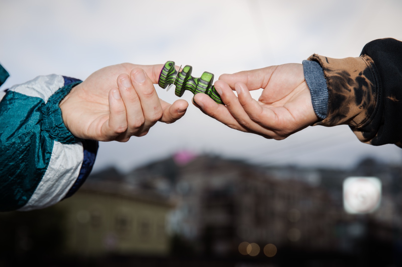 Two hands passing a green Edger from one person to another