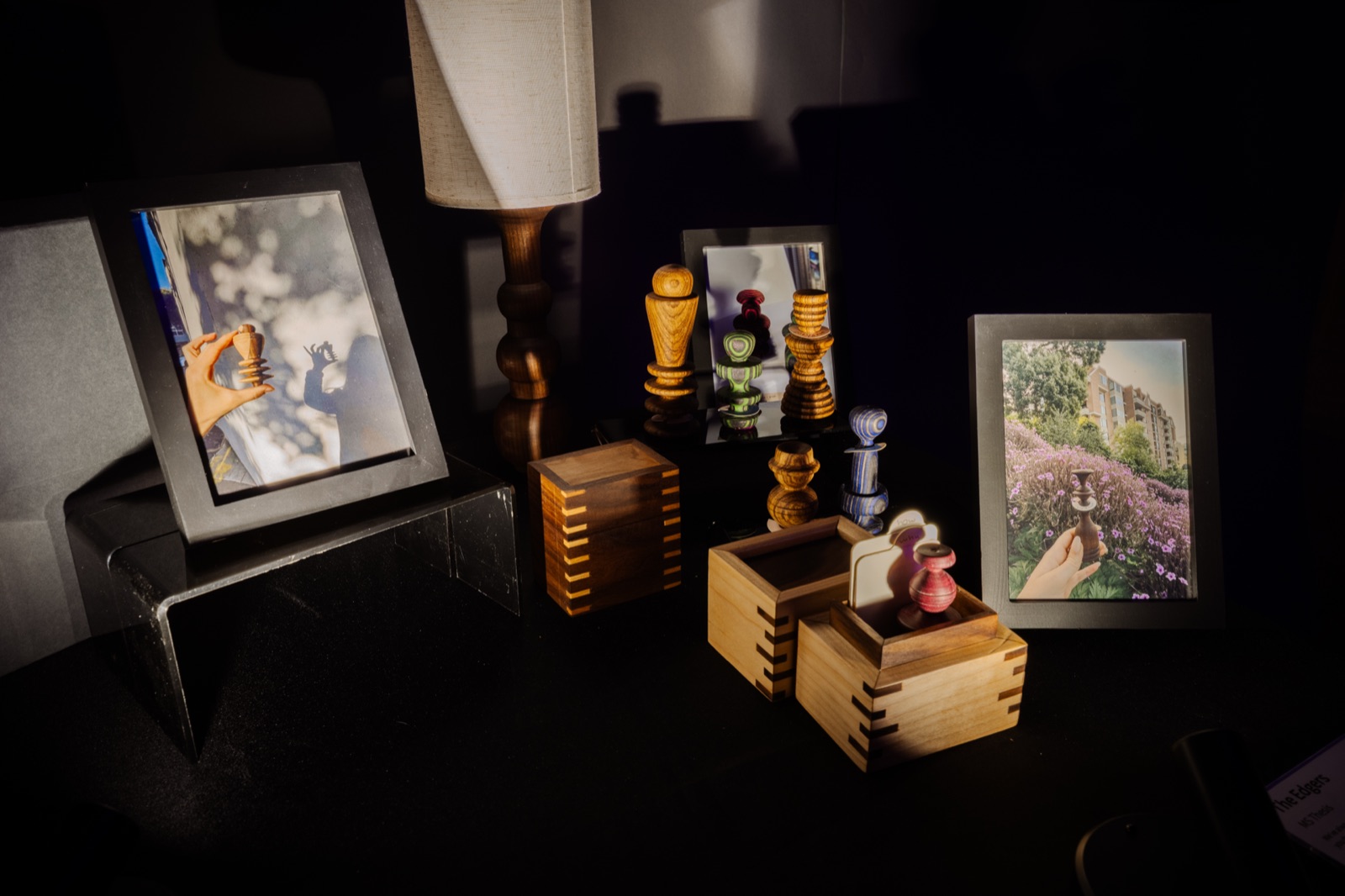 Edgers displayed in wooden boxes beside framed holder photographs, on a dark plinth under a lamp