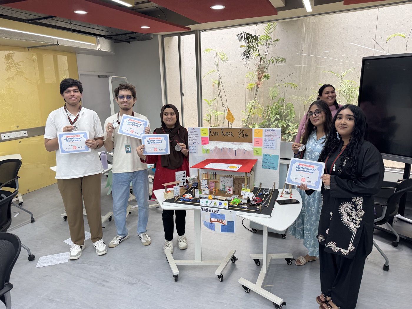 A team with their Rain Rider Hub prototype and completion certificates at the showcase